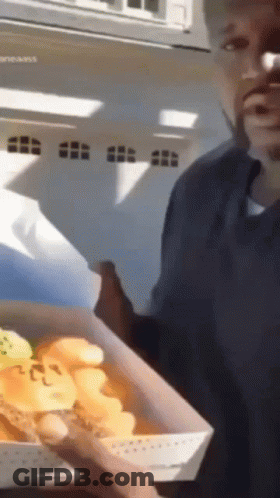 A Man Is Holding A Box Of Food That Says ' Chicken ' On It GIF