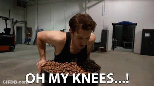 A Man Is Holding A Bucket Of Nuts With The Words Oh My Knees Written Below Him GIF
