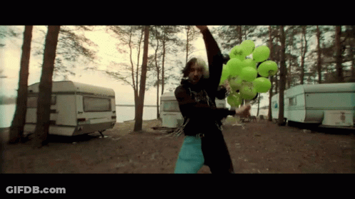 A Man Is Holding A Bunch Of Green Balloons With A Sticker That Says ' A ' On It GIF