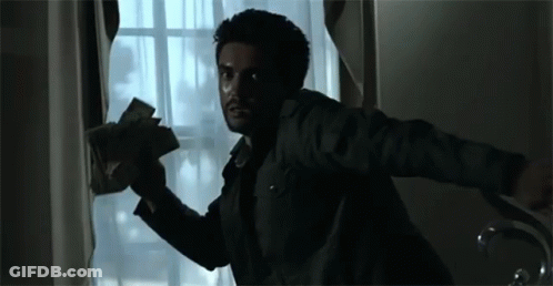 A Man Is Holding A Bunch Of Money In His Hand While Looking Out Of A Window . GIF