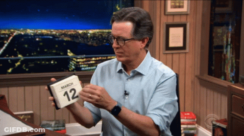 A Man Is Holding A Calendar That Says March 12 On It GIF