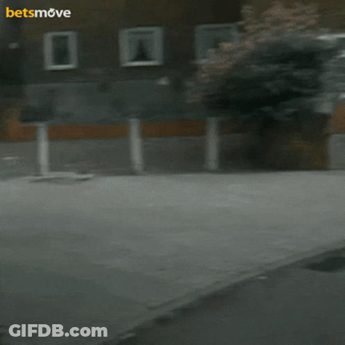 A Man Is Holding A Camera In Front Of A Building With The Words Betsmove On The Bottom GIF