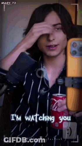 A Man Is Holding A Can Of Coca Cola While Taking A Picture Of Himself . GIF