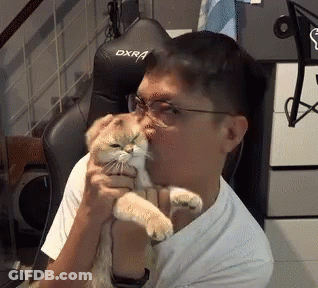 A Man Is Holding A Cat In Front Of A Black Dxr Gaming Chair GIF