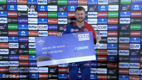 A Man Is Holding A Cheque That Says Man Of The Match On It GIF