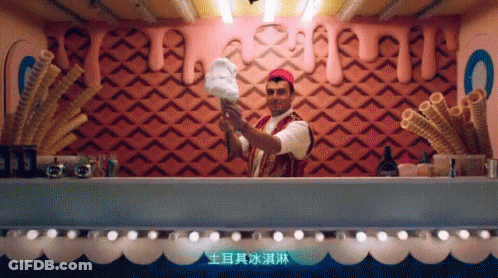 A Man Is Holding A Cotton Candy Cone In Front Of A Wall With Chinese Writing GIF