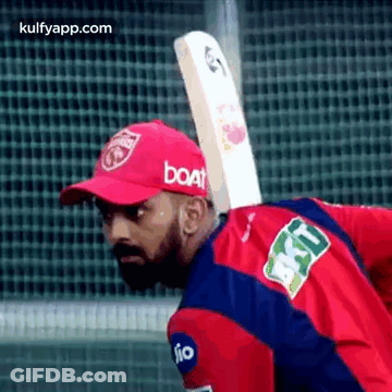 A Man Is Holding A Cricket Bat On His Back . GIF