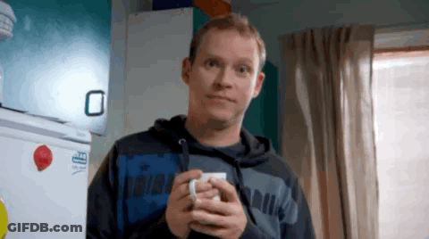 A Man Is Holding A Cup Of Coffee In His Hands And Making A Funny Face . GIF