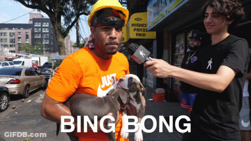 A Man Is Holding A Dog In Front Of A Sign That Says Higher Prices Paid GIF