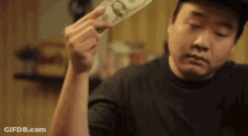A Man Is Holding A Dollar Bill In His Hand And Looking At It . GIF