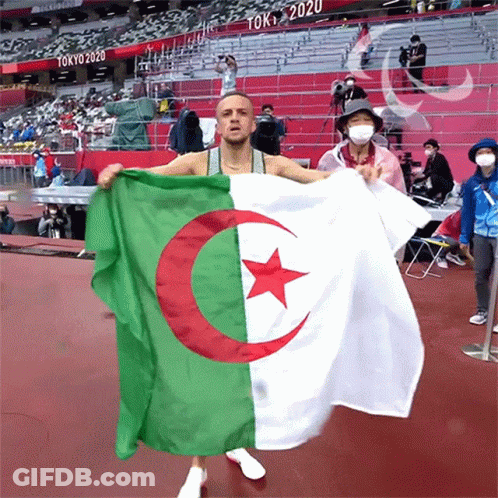 A Man Is Holding A Flag That Says Tokyo 2020 On It GIF