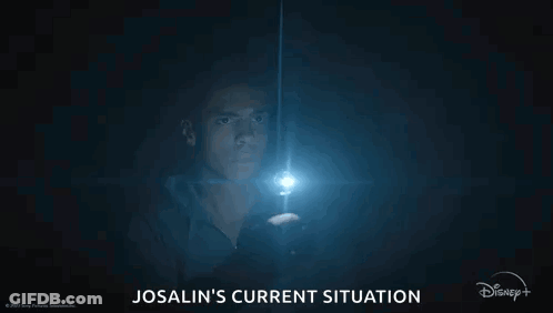 A Man Is Holding A Flashlight In The Dark And Looking At It . GIF