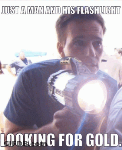A Man Is Holding A Flashlight With The Caption " Just A Man And His Flashlight Looking For Gold " GIF