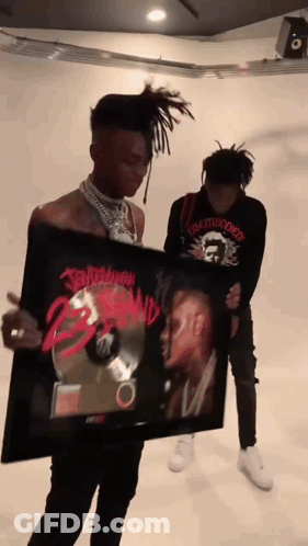 A Man Is Holding A Framed Picture Of A Man With Dreadlocks And The Word Tomorrow On It GIF