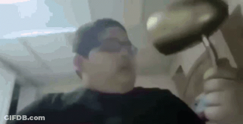 A Man Is Holding A Frying Pan Over His Head In A Blurry Photo . GIF