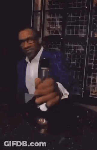 A Man Is Holding A Glass And A Bottle Of Wine GIF