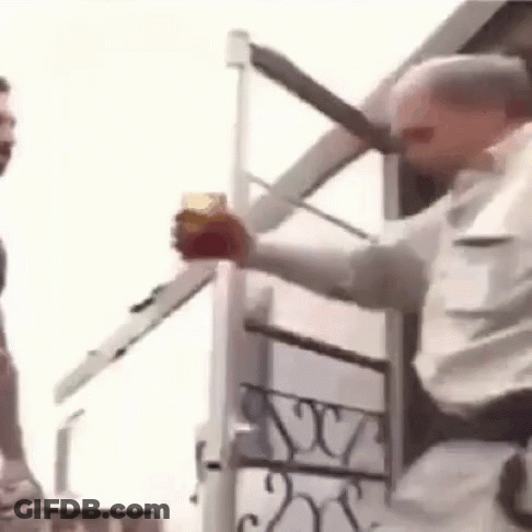 A Man Is Holding A Glass Of Beer And A Knife In Front Of A Building . GIF