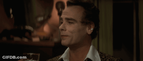 A Man Is Holding A Glass Of Beer In His Hand GIF