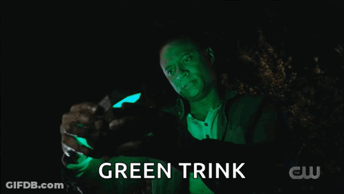 A Man Is Holding A Green Object That Says Green Trink On It GIF