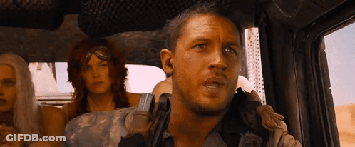 A Man Is Holding A Gun In A Car With Two Women . GIF