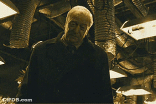 A Man Is Holding A Gun In A Dark Room GIF