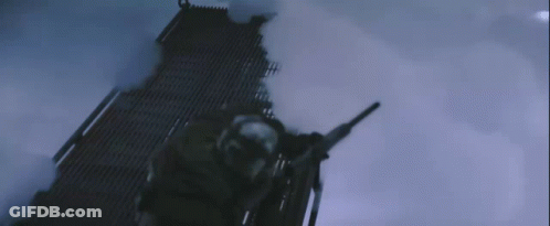 A Man Is Holding A Gun In A Dark Room With Smoke Coming Out Of It GIF
