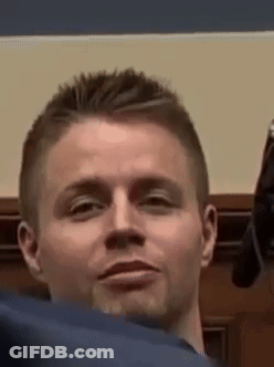A Man Is Holding A Gun In His Hand And Making A Face . GIF