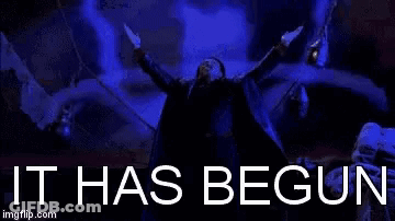 A Man Is Holding A Gun In His Hand In Front Of A Blue Background With The Words `` It Has Begun '' Written On It . GIF