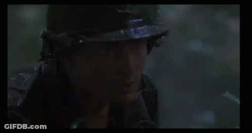 A Man Is Holding A Gun In The Woods . GIF