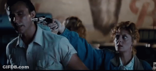 A Man Is Holding A Gun To His Head While A Woman Holds A Gun To His Back . GIF