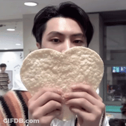 A Man Is Holding A Heart Shaped Tortilla Chip GIF