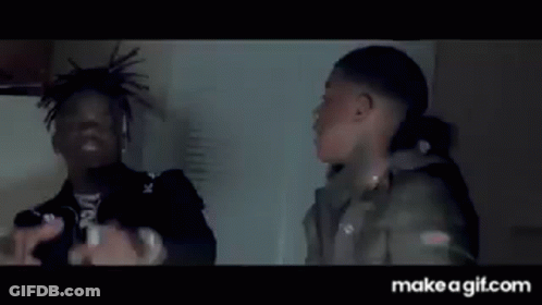 A Man Is Holding A Knife In His Hand While Another Man Is Standing Next To Him . GIF