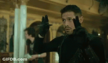 A Man Is Holding A Knife In His Hand While Wearing A Black Glove . GIF