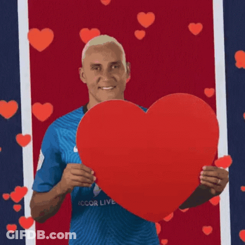 A Man Is Holding A Large Red Heart In His Hands GIF