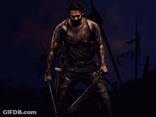 A Man Is Holding A Large Sword In Front Of A Fire GIF