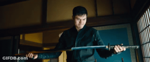 A Man Is Holding A Large Sword In His Hands GIF