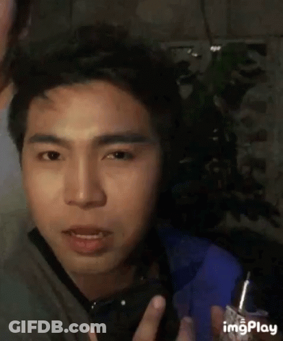 A Man Is Holding A Lighter In His Hand And Making A Face . GIF