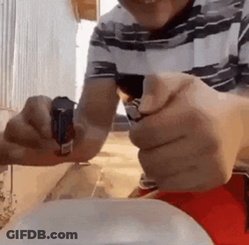 A Man Is Holding A Lighter In His Hand While Sitting At A Table . GIF