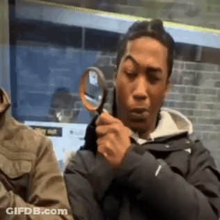 A Man Is Holding A Magnifying Glass And Looking Through It . GIF