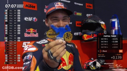 A Man Is Holding A Medal In Front Of A Red Bull Sign GIF