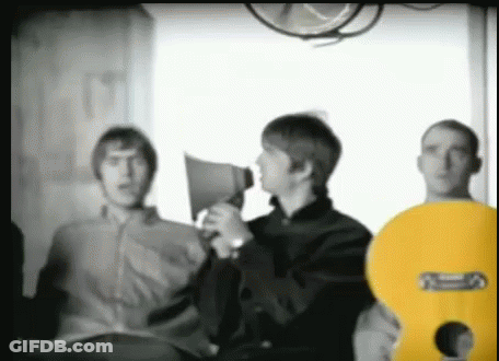 A Man Is Holding A Megaphone While Standing Next To Two Other Men . GIF