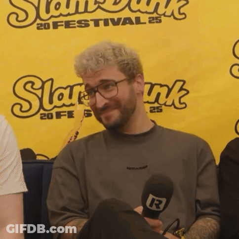 A Man Is Holding A Microphone In Front Of A Banner That Says Slam Dunk GIF