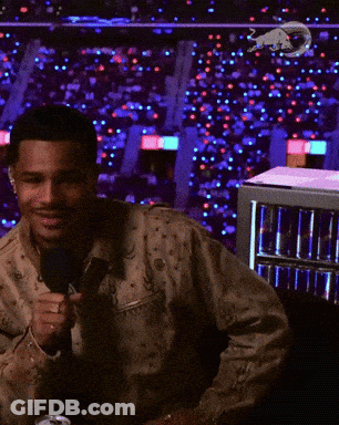 A Man Is Holding A Microphone In Front Of A Fridge Full Of Red Bull Cans GIF