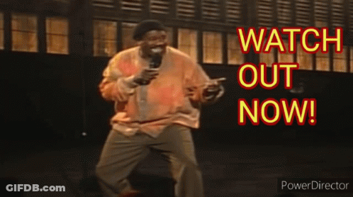 A Man Is Holding A Microphone In Front Of A Sign That Says Watch Out Now .. GIF
