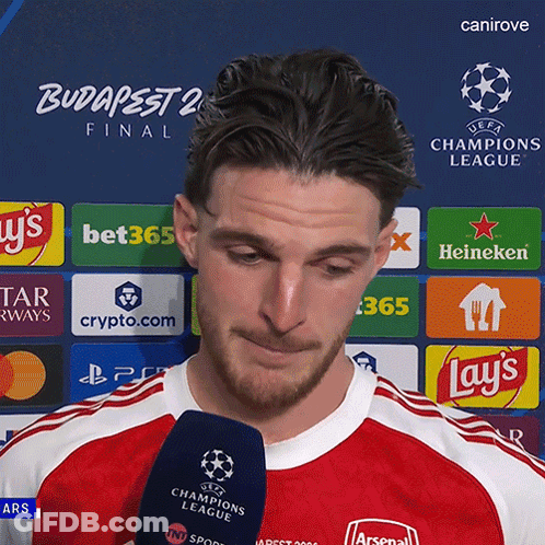 A Man Is Holding A Microphone In Front Of A Uefa Champions League Logo GIF