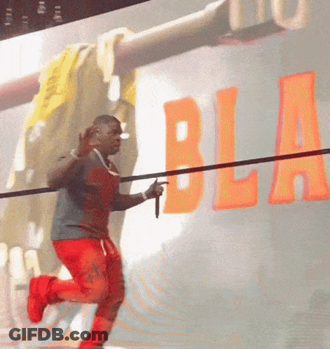 A Man Is Holding A Microphone In Front Of A Wall That Has The Word Bla On It GIF