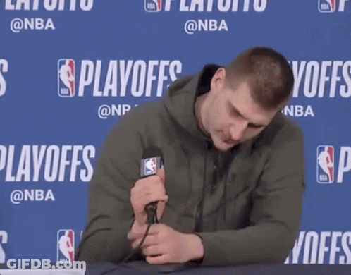 A Man Is Holding A Microphone In Front Of A Wall That Says Playoffs On It GIF