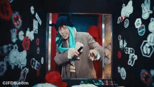 A Man Is Holding A Microphone In Front Of A Wall With Stickers On It GIF