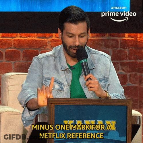 A Man Is Holding A Microphone In Front Of An Amazon Prime Video Sign GIF