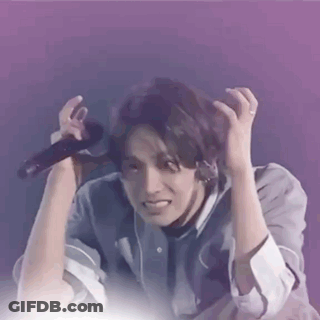 A Man Is Holding A Microphone In His Hand And Making A Face . GIF